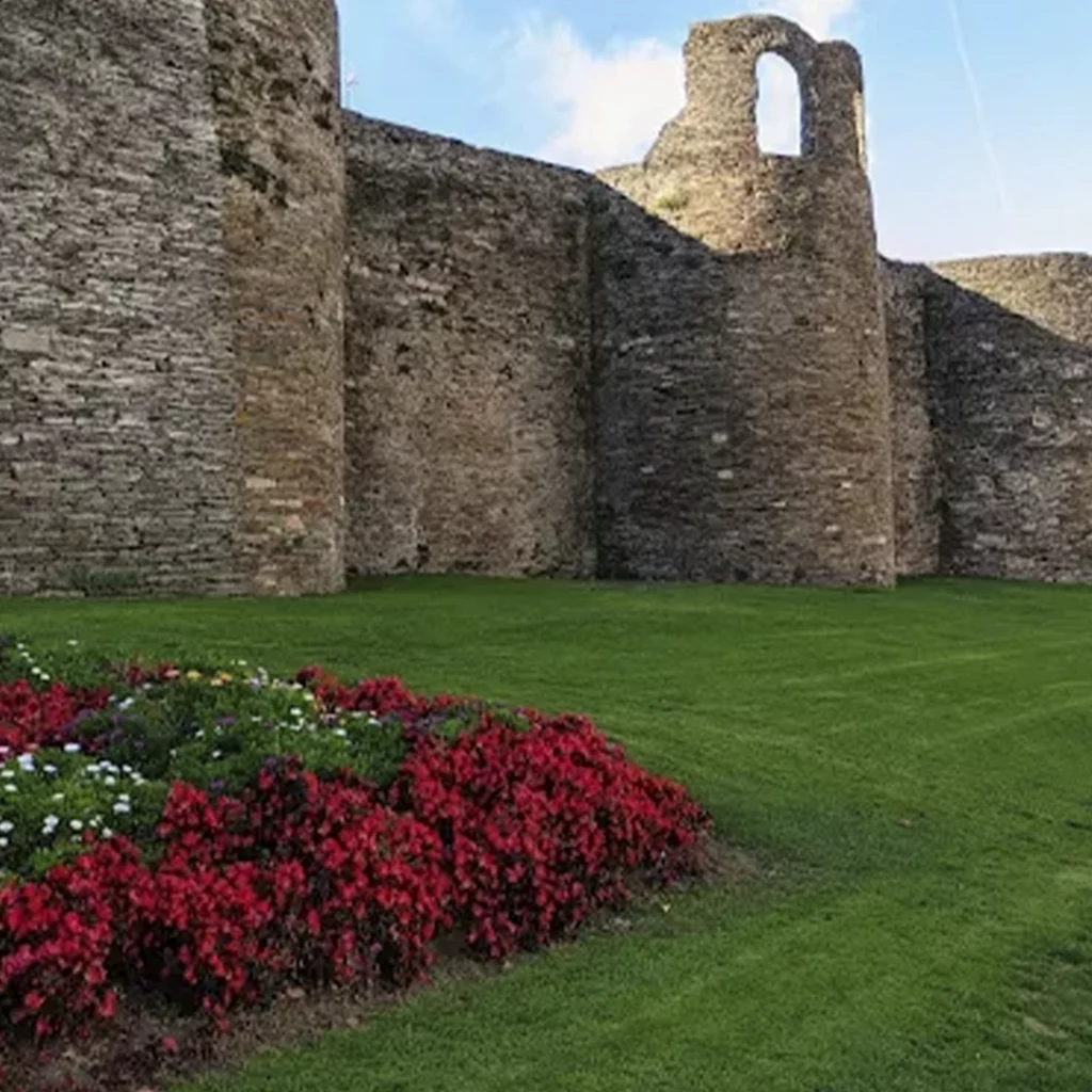 Muralla Romana de Lugo con zona ajardinada y flores rojas en primer plano